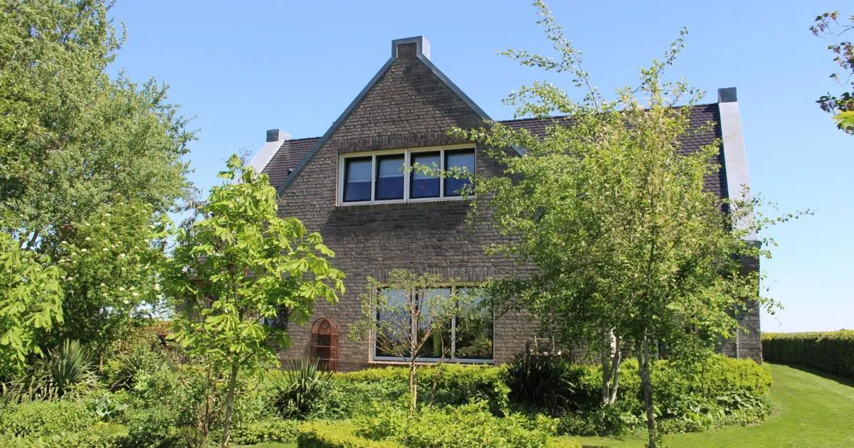 Buitenaanzicht van bed & breakfast Zonnedauw, een karakteristiek bakstenen pand met tuin
